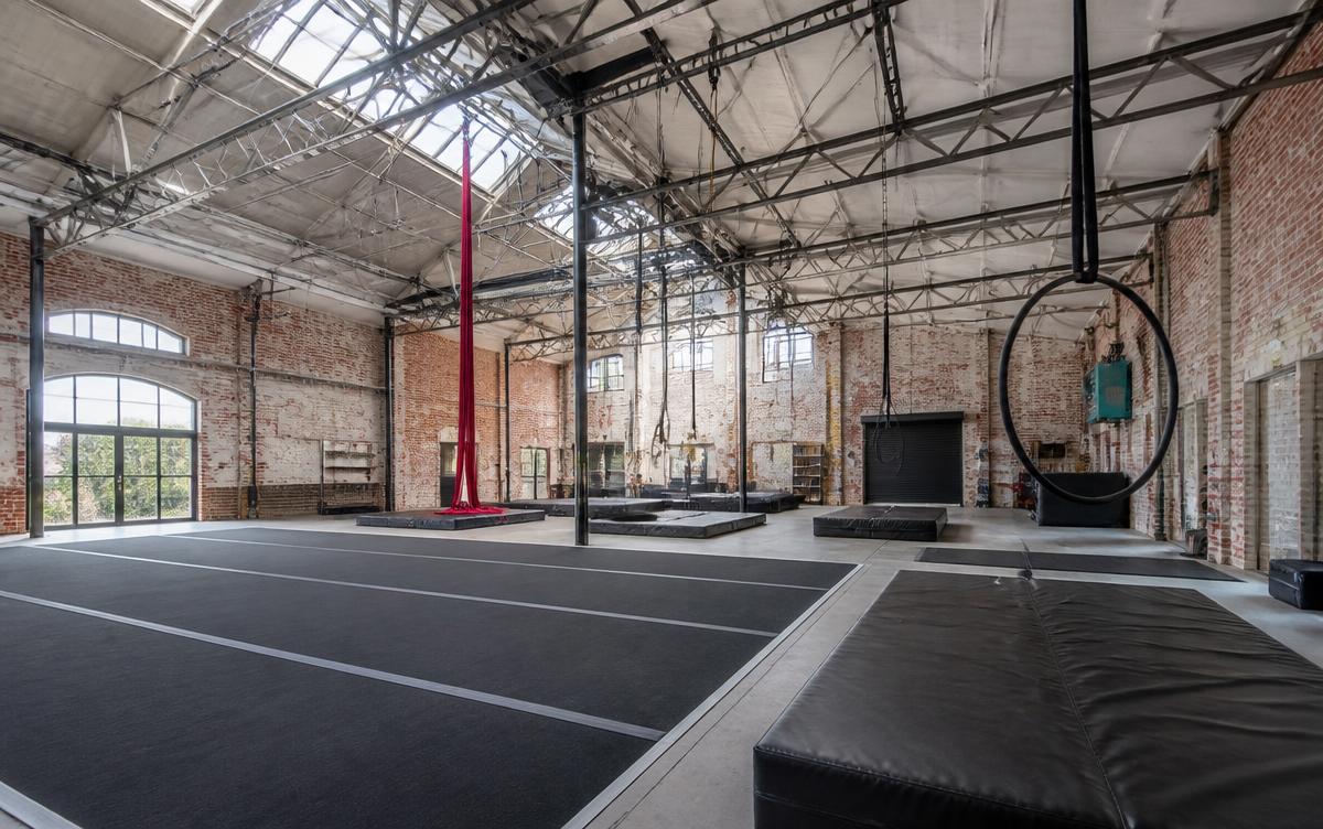 A converted warehouse circus venue with rigging points, aerial silks and crash matting